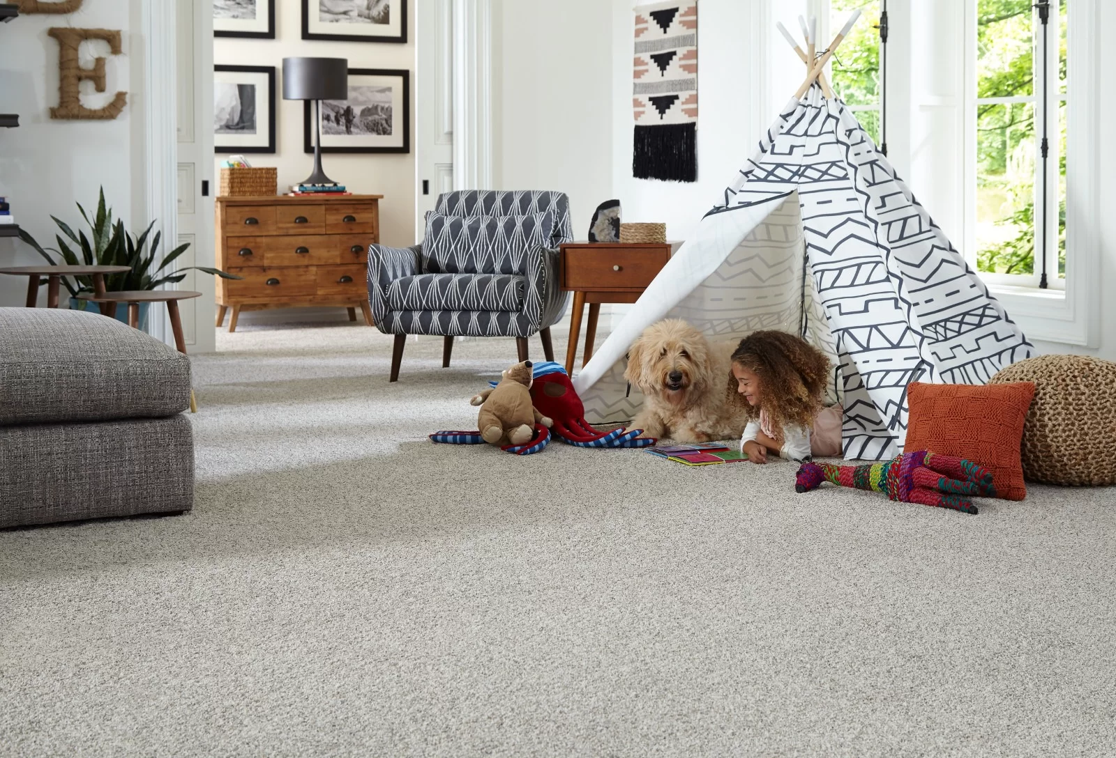 Family room with plush carpet, a child and dog playing under a teepee